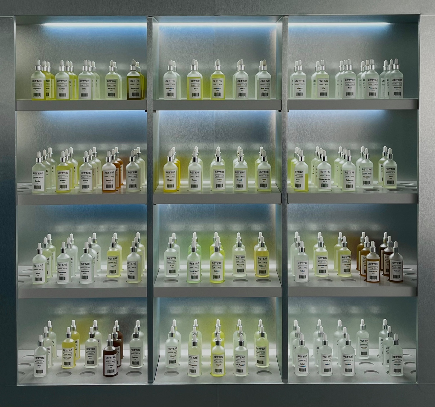 Modular metal display cabinet containing clear glass perfume bottles with white labels